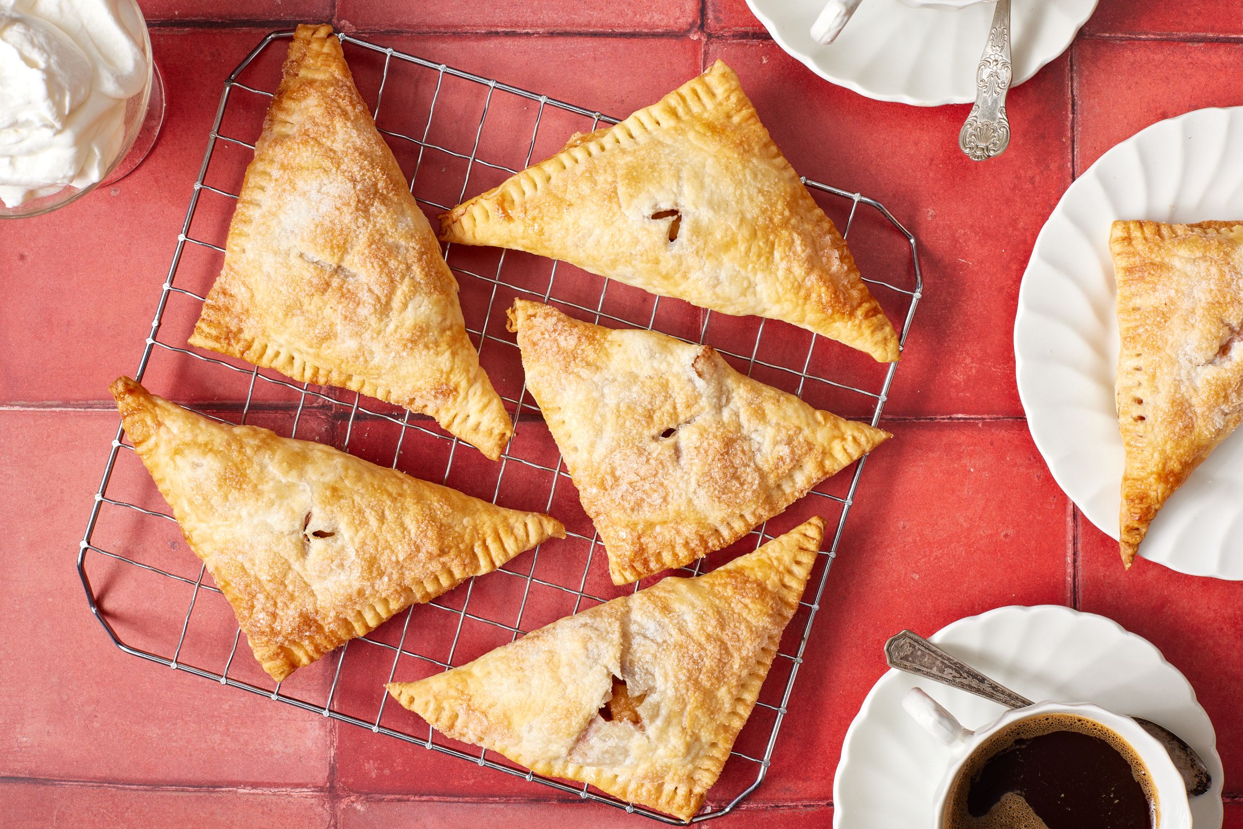 Golden apple turnovers on the cooling rack, served with coffee on the side.