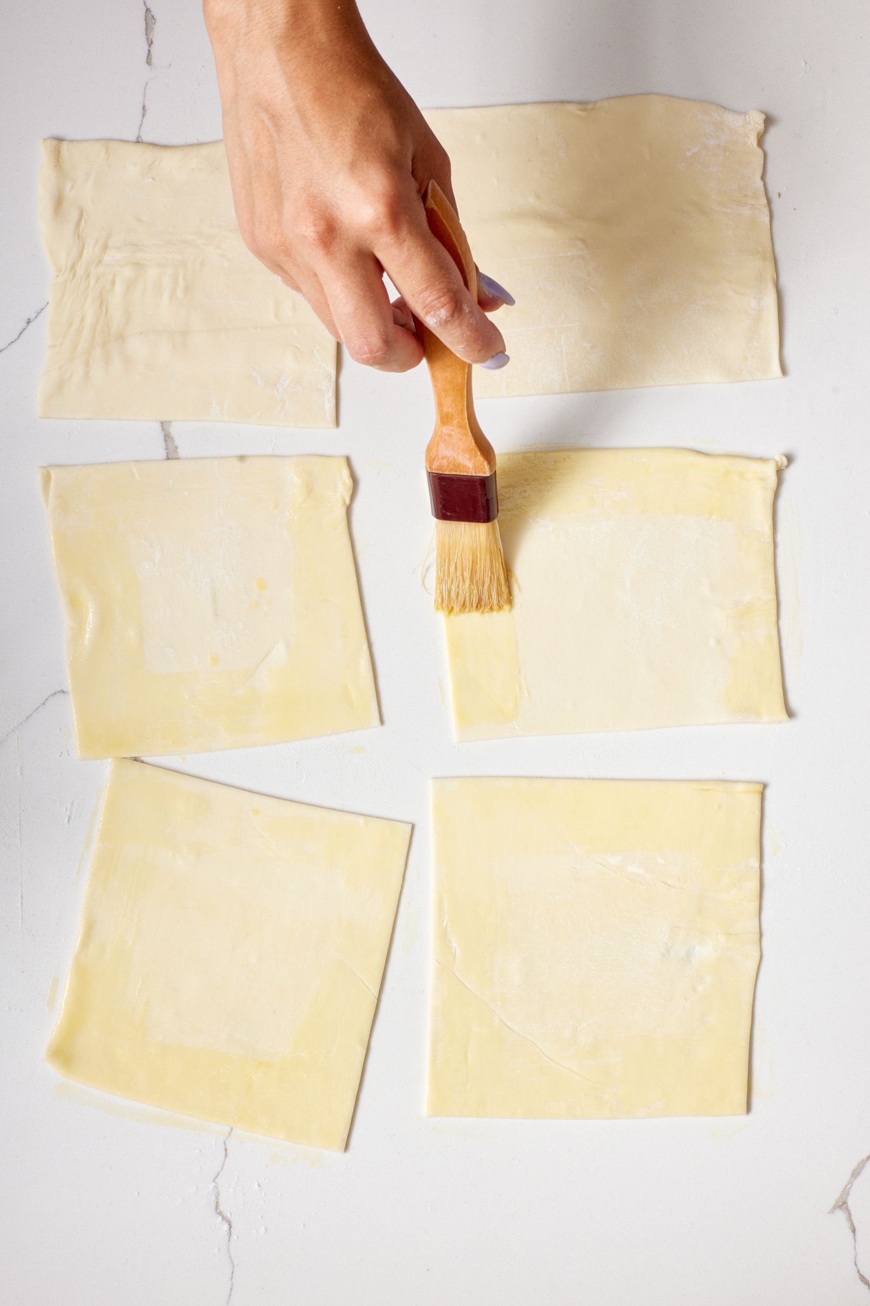Place pastry squares on the baking tray and brush the squares edges with egg wash.
