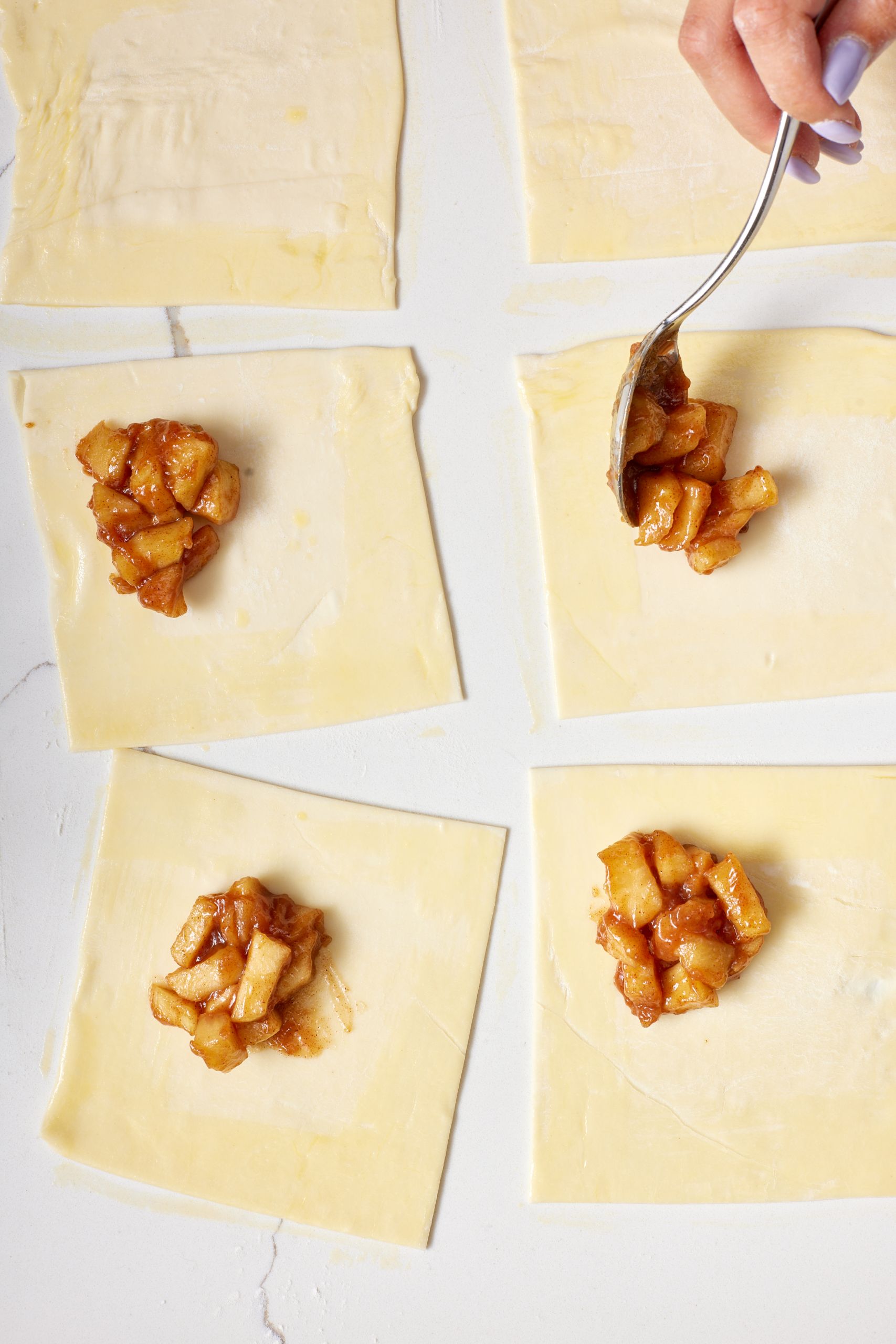 Fill and fold: Spoon 2 tablespoons of apple mixture into the center of each square, then fold over to make a triangle.