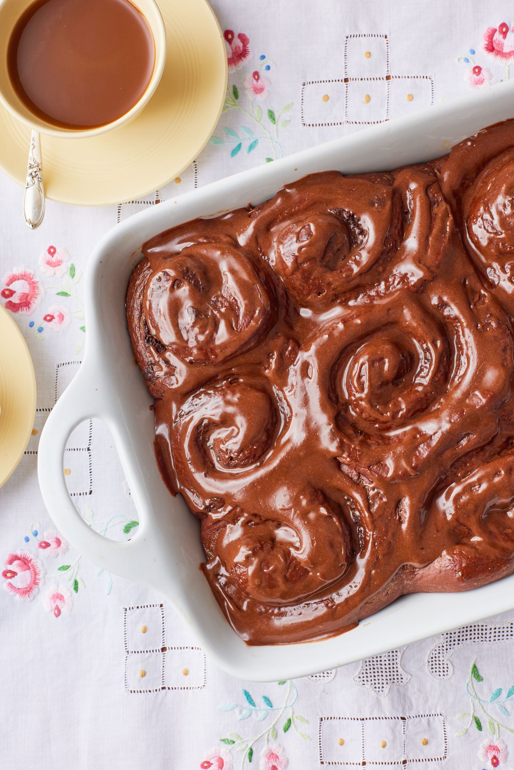 Chocolate Cinnamon Rolls glazed with chocolate and served with coffee on the side.
