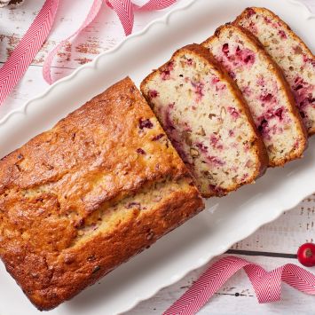 Top down view of half loaf of Cranberry Banana Bread with three slices served on a platter.