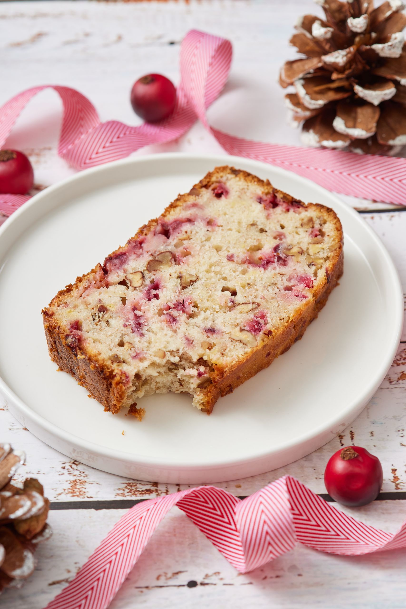 A slice of Cranberry Banana Bread with one bite taken , served on a plate. 