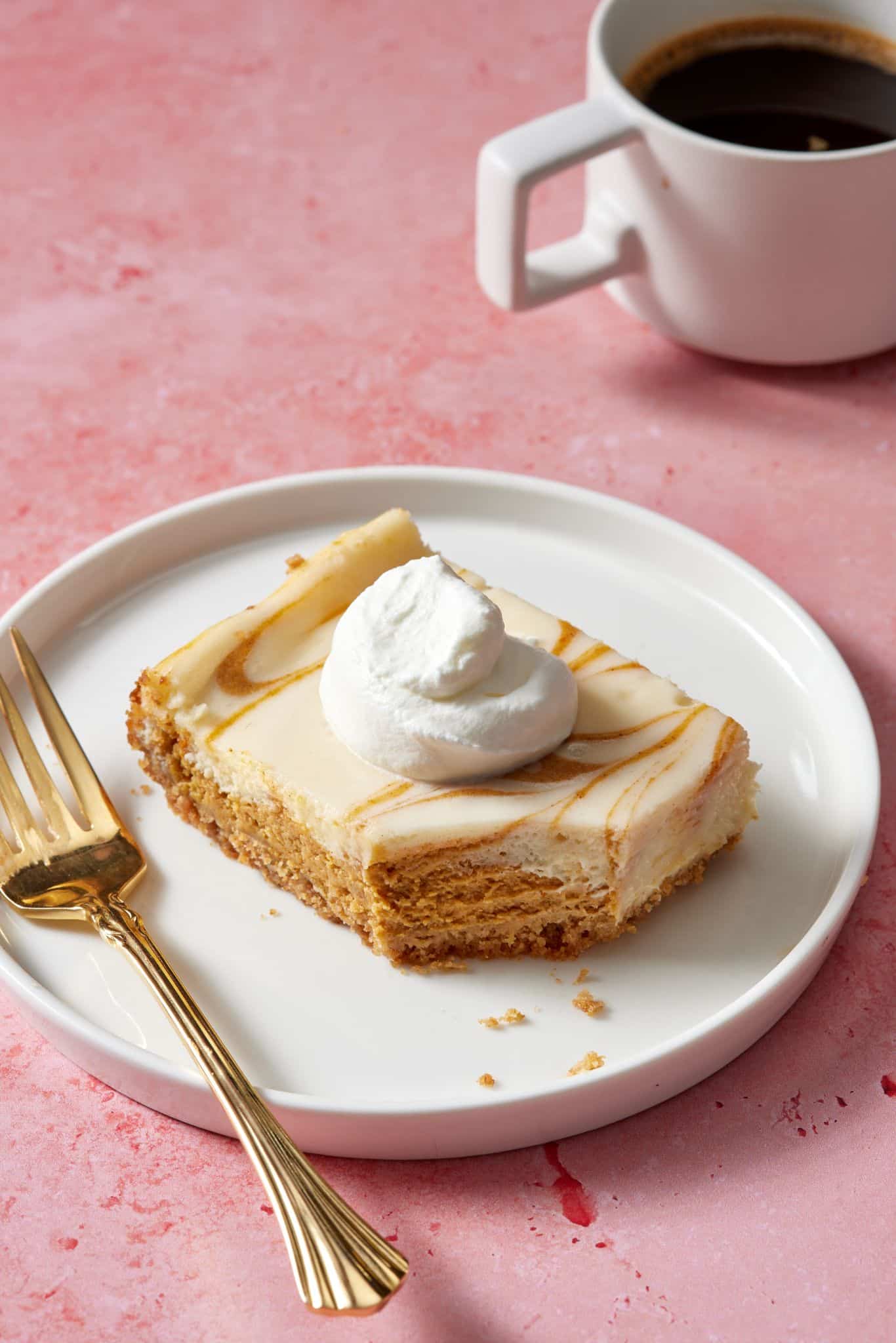 Pumpkin Cheesecake Bars13 A square of pumpkin cheesecake bar served with whipped cream and coffee.
