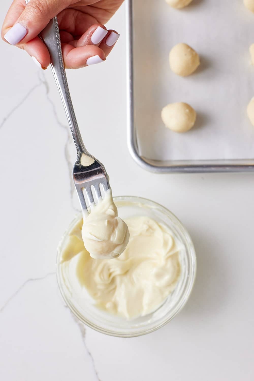 Eggnog Truffles6 Use a fork to dip each truffle in the melted chocolate, allowing the excess chocolate to drip off before returning to the parchment paper.