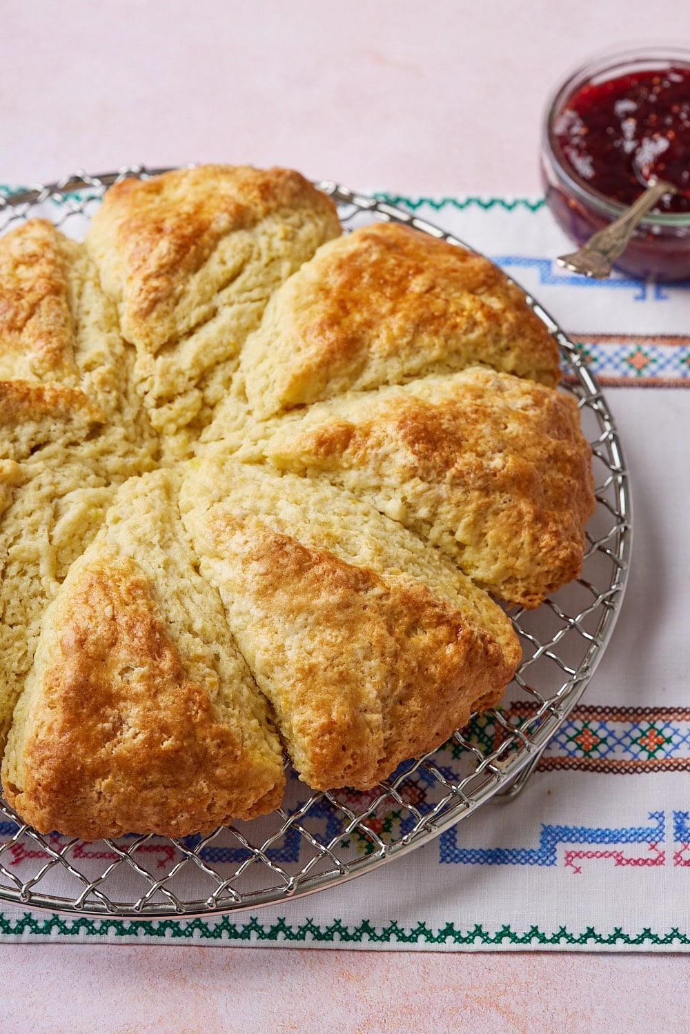 Irish Soda Bread Scones8 Golden brown soda bread scone on a cooling rack served with jam on the side.