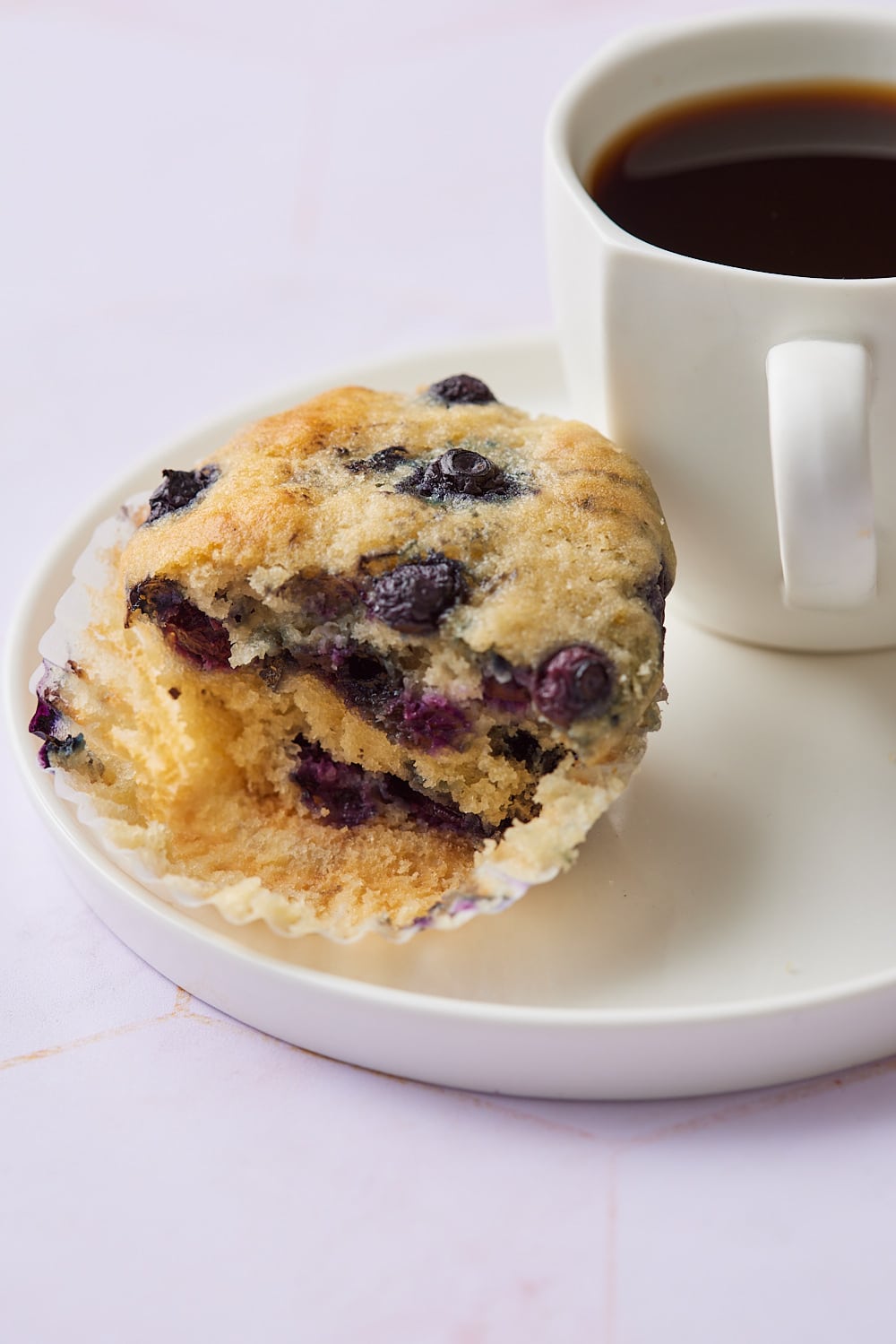 Sourdough Blueberry Muffins8 Half of a sourdough blueberry muffin served a cup of coffee.