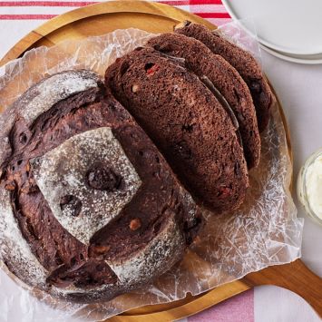 Top down view of a loaf of Chocolate Sourdough Bread with soft crumb and rustic crust, served with butter on the side.