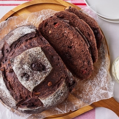 Top down view of a loaf of Chocolate Sourdough Bread with soft crumb and rustic crust, served with butter on the side.