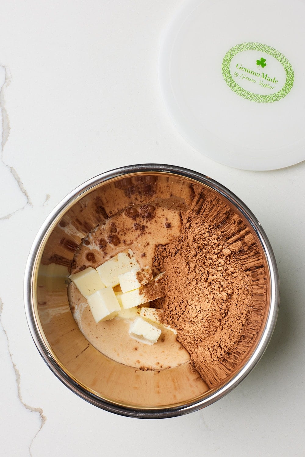 Add butter, cocoa, and milk to bowl: In a medium microwave-safe bowl, add the butter, unsweetened cocoa powder, and whole milk.