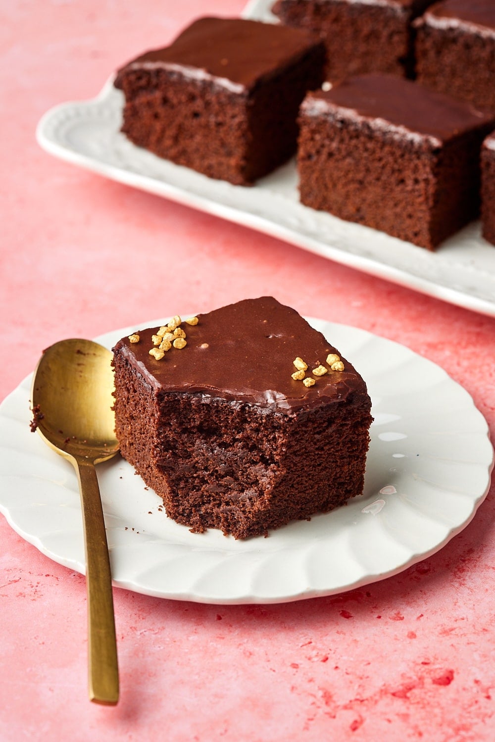 A close-up shot at a slice of chocolate cake with frosting with one bite taken. 