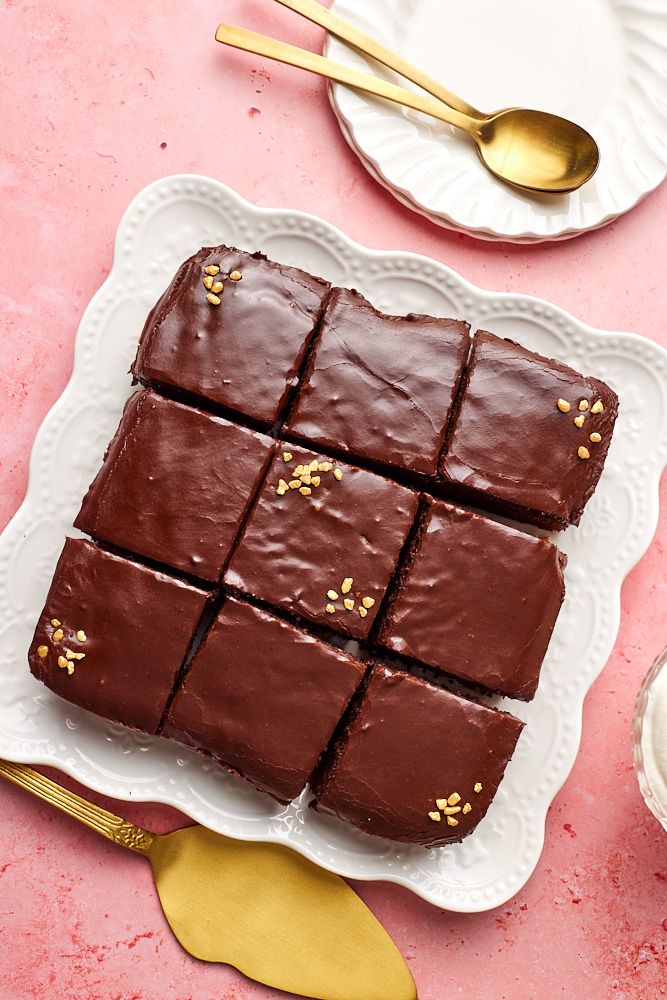 Top down view of chocolate cake cut into nine squares. The cake is topped with 1 minute chocolate frosting. 