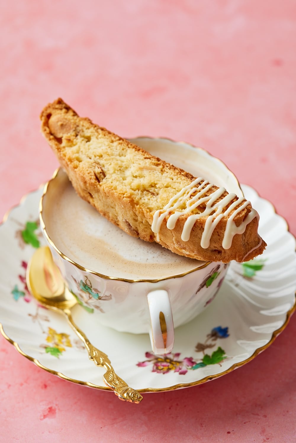 A slice of Lemon Biscotti drizzled with glaze and is served with tea. 