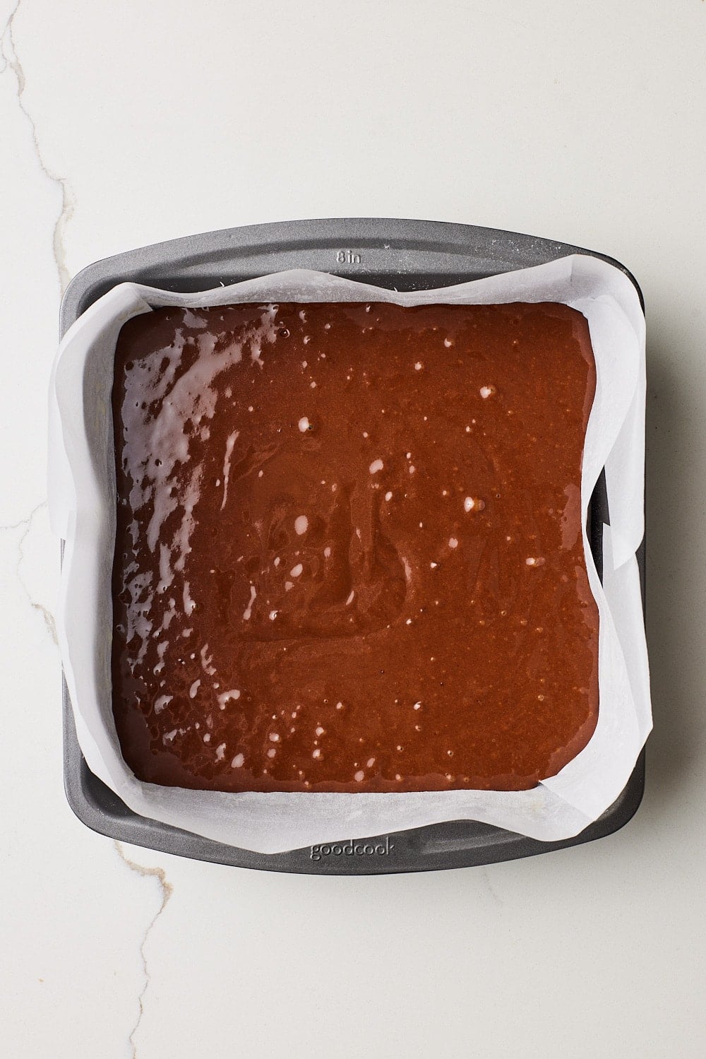 One bowl chocolate cake5 One Bowl Chocolate Cake batter added to a parchment-lined baking pan.