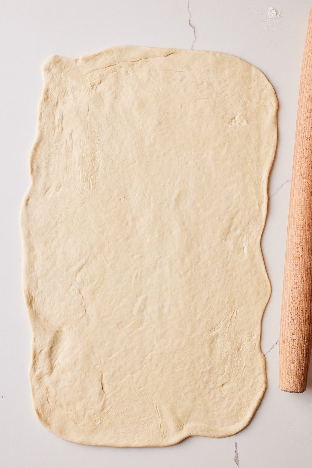 Sheet Pan Pizza2 A rectangular pizza dough for Sheet Pan Pizza with a rolling pin next to it.