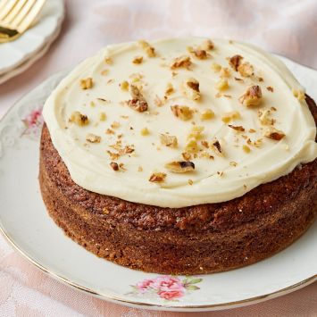 A moist small carrot cake frosted with cream cheese frosting sprinkled with chopped walnuts.