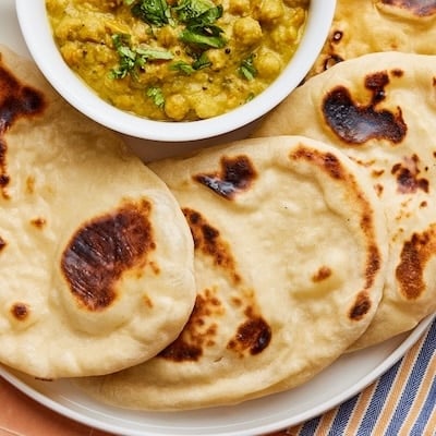 Top-down view of sourdough naan with a bowl of chickpeas dip.