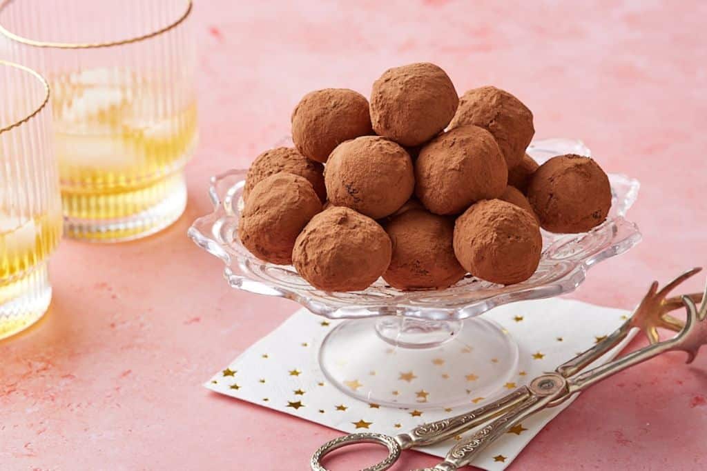 Whisky truffles coated with cocoa powder displayed on a cake stand.