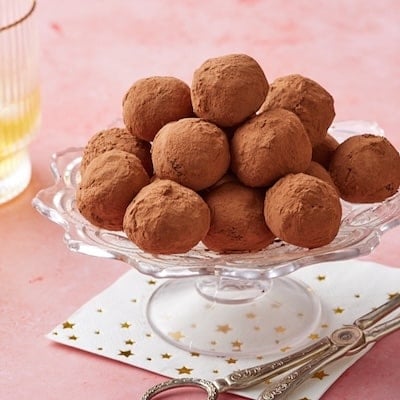 Whisky truffles coated with cocoa powder displayed on a cake stand.