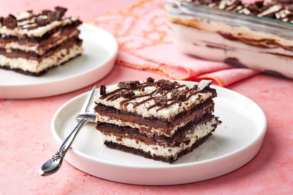 Two pieces of layered chocolate icebox cake served on dessert plates, with the remaining cake in the pan.