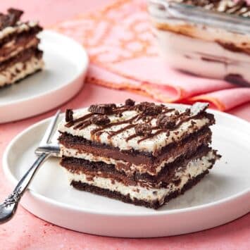 Two pieces of layered chocolate icebox cake served on dessert plates, with the remaining cake in the pan.