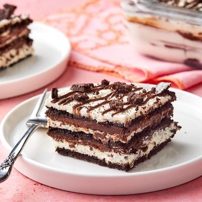 Two pieces of layered chocolate icebox cake served on dessert plates, with the remaining cake in the pan.