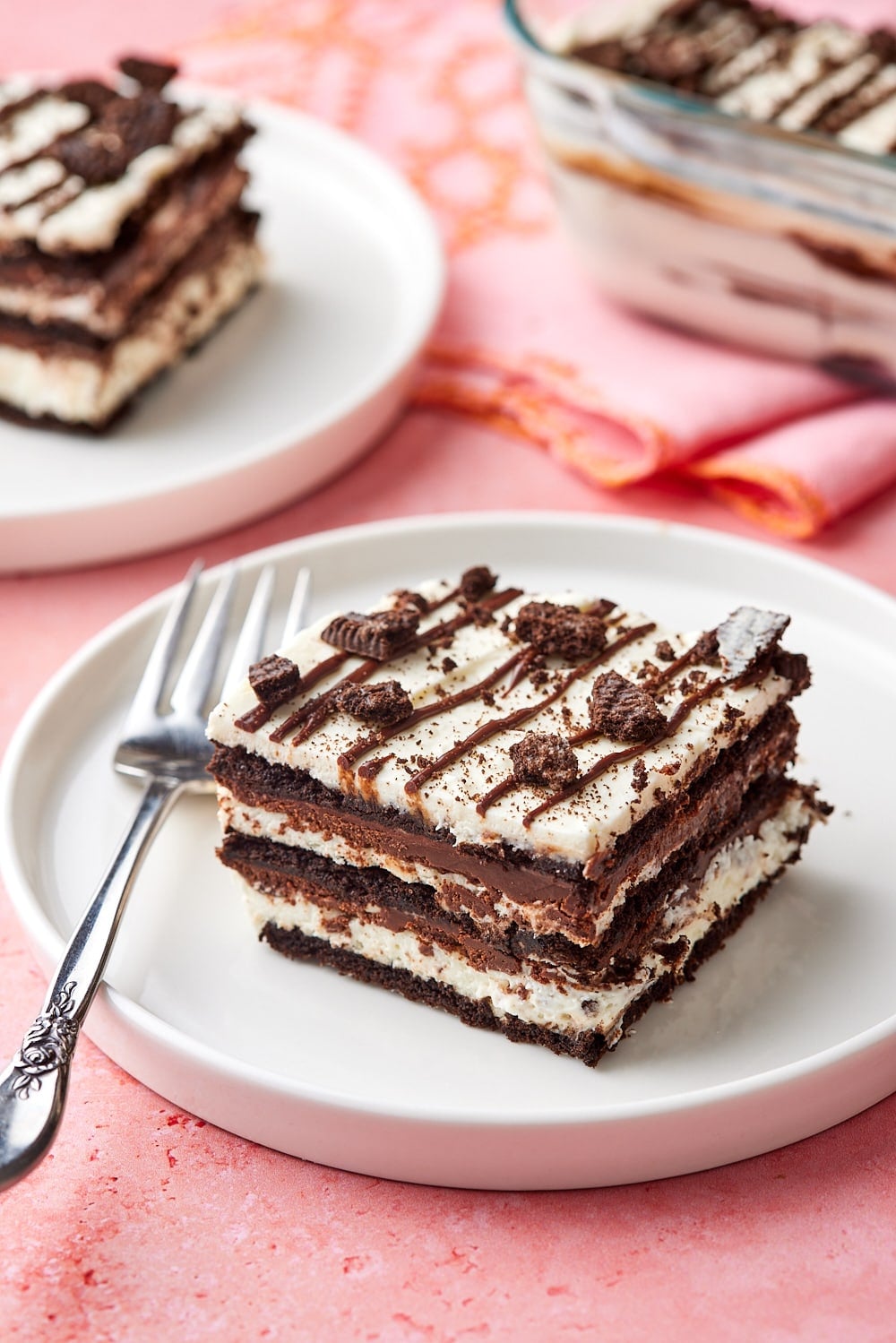 Two pieces of layered chocolate icebox cake served on dessert plates, with the remaining cake in the pan.