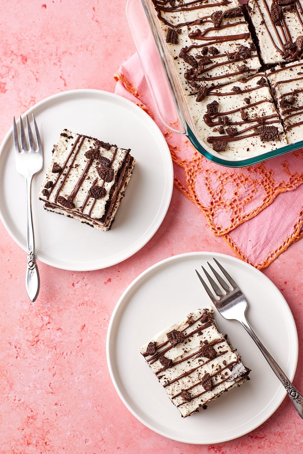 Top-down view of two pieces of layered chocolate icebox cake served on dessert plates, with the remaining cake in the pan.
