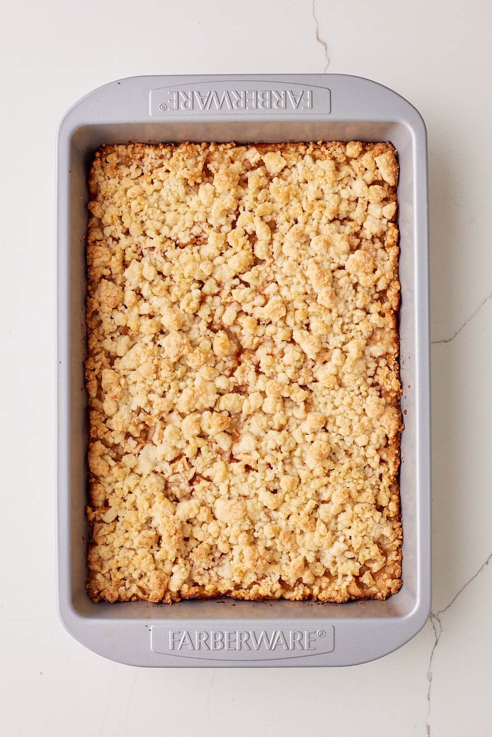 Top-down a tray of apple crumble bars baked golden. 