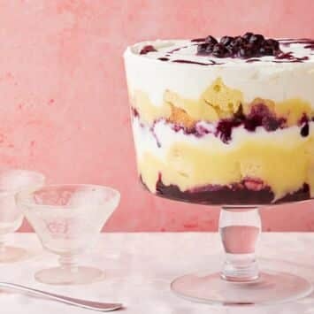 Lemon Blueberry Triffle in a big glass bowl with layers of cakes, filling, lemon curd, and whipped cream.