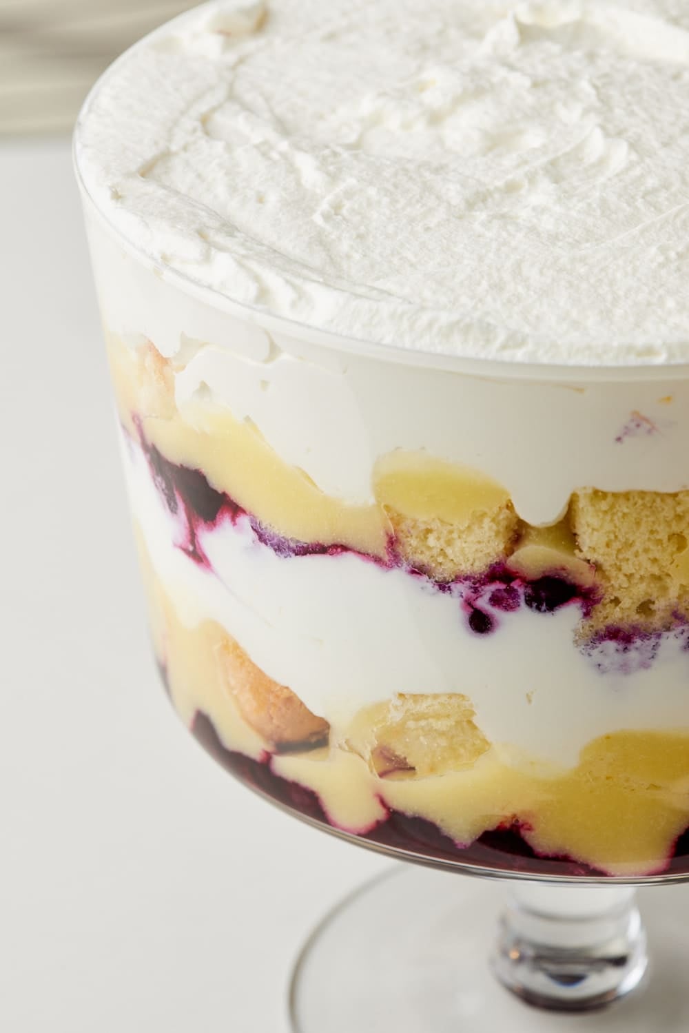 A close-up shot from the side of Lemon Blueberry Truffle shows the layers of blueberry filling, cake, whipped cream, and lemon curd. 