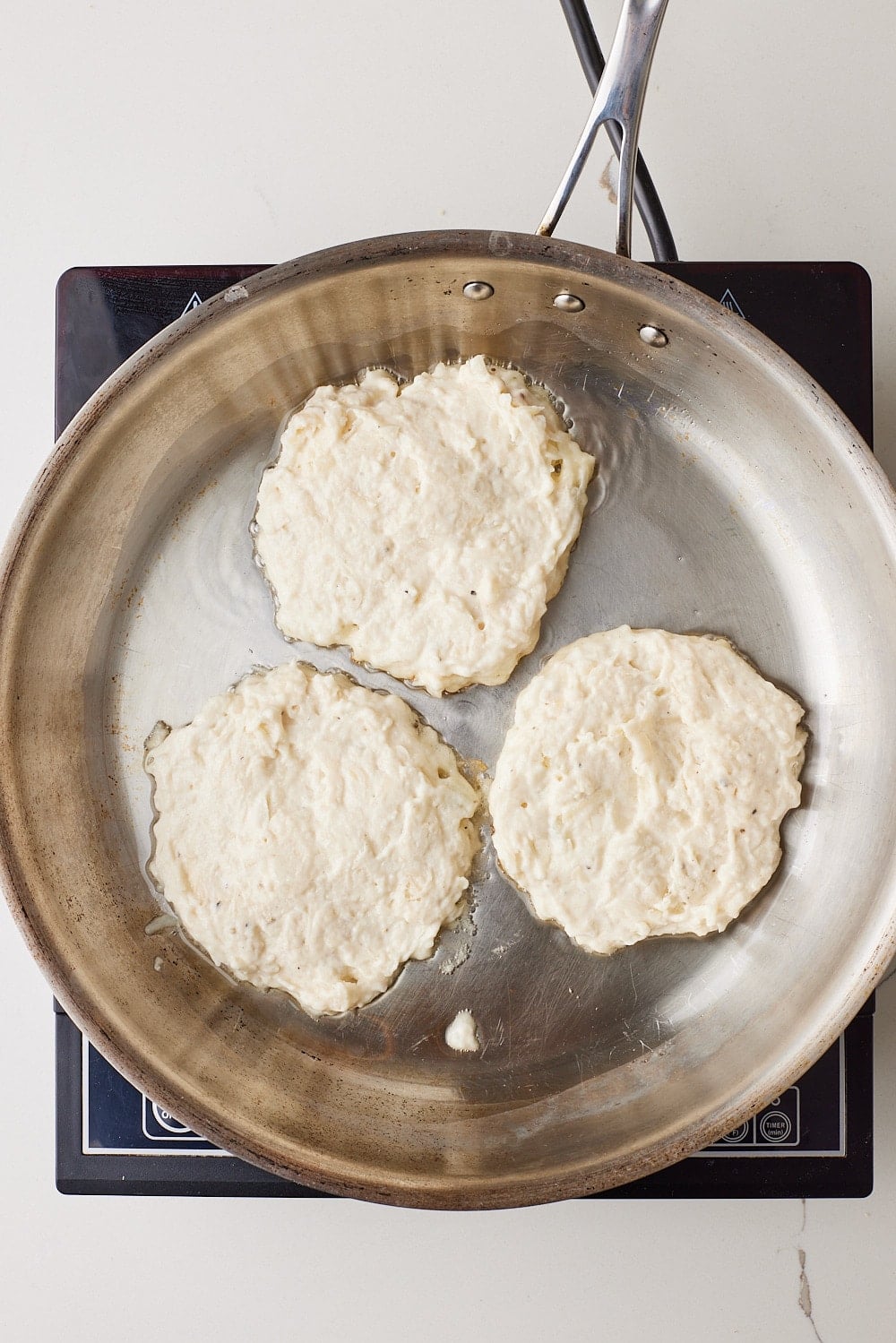 Boxty9 Three scoops of Boxty batter cooking in the pan.