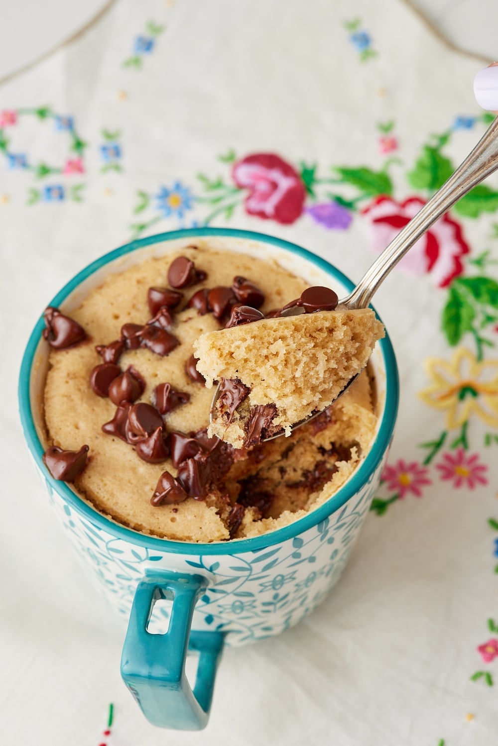 A scoop of chocolate chip mug cake shows its moist crumb. 