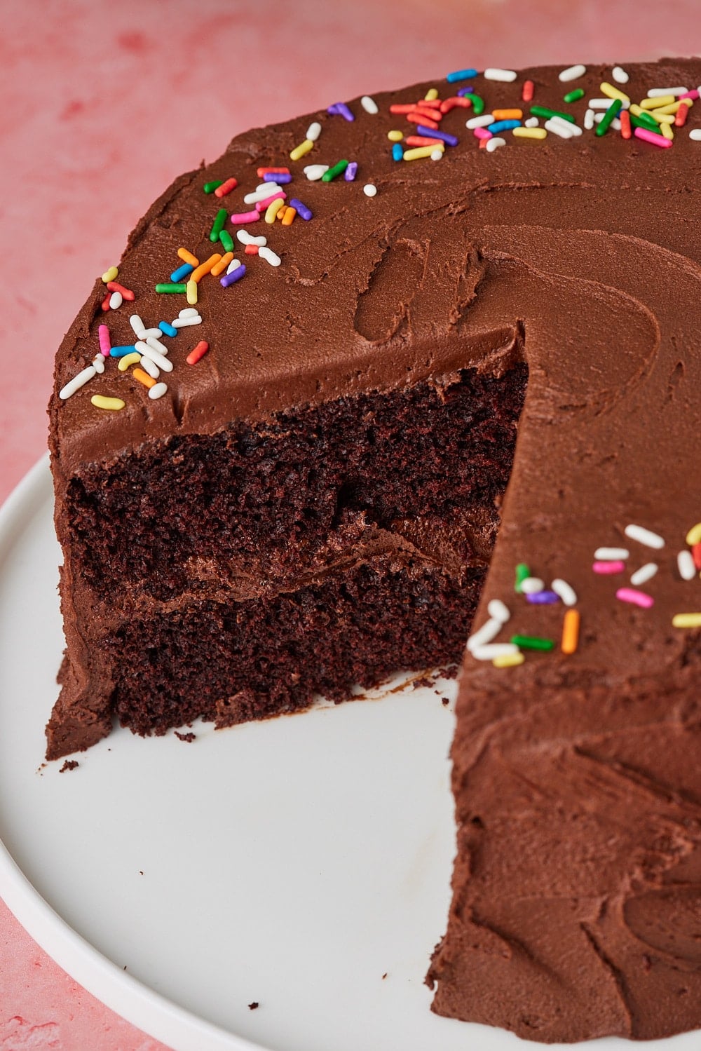 Chocolate Mayo Cake14 Slice removed from a rich Chocolate Mayonnaise Cake frosted with smooth chocolate buttercream and topped with colorful rainbow sprinkles, revealing its moist, tender chocolate crumb and creamy chocolate filling.