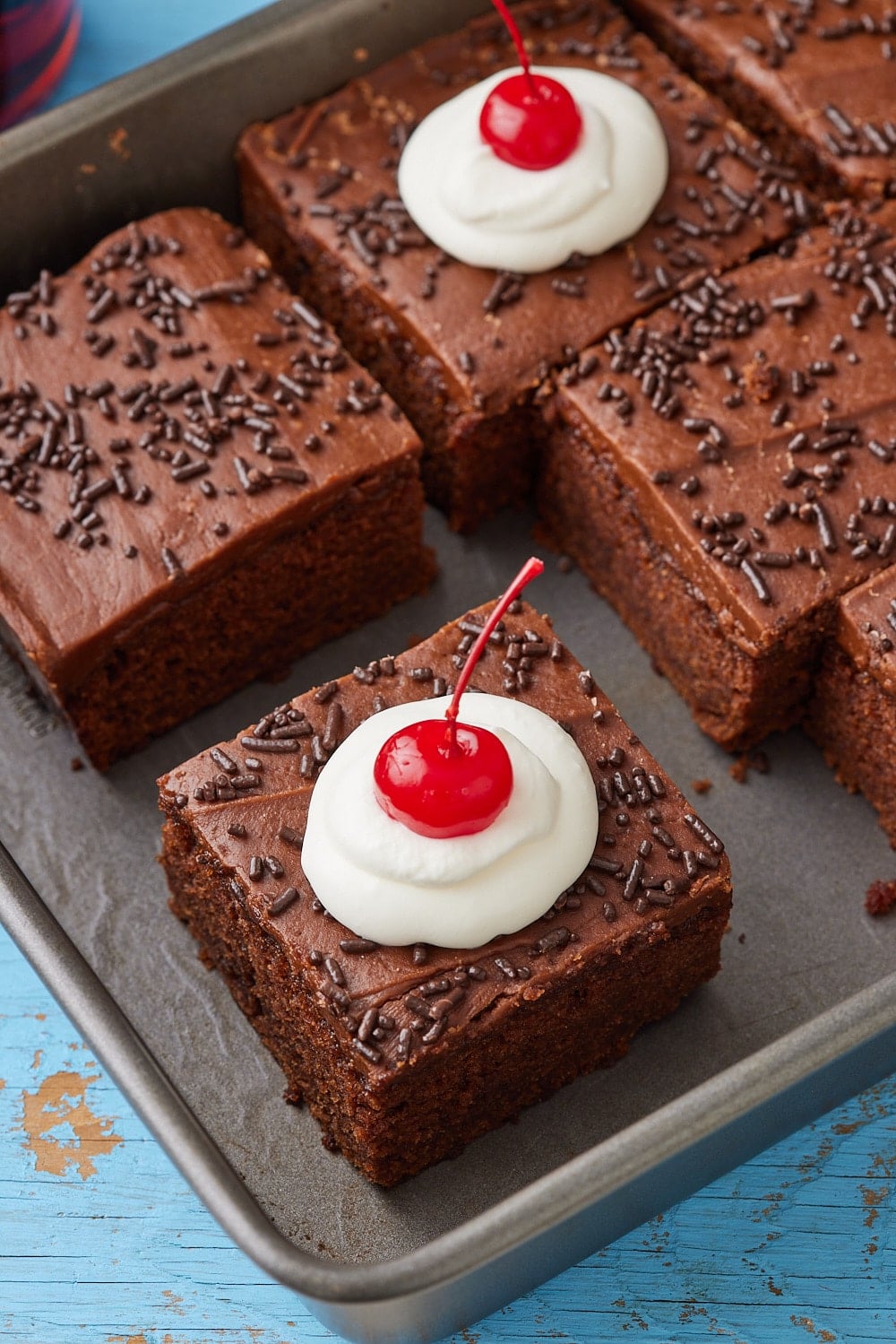 Coca Cola Cake16.1 Squares of Coca Cola Cake with rich frosting, chocolate sprinkles, whipped cream and cherries on top.