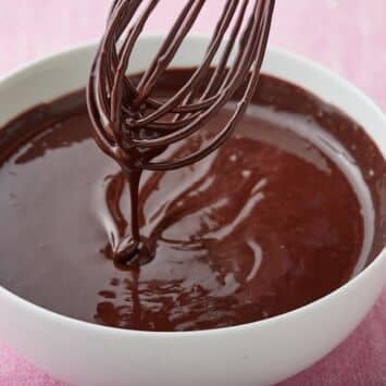 Silky thick hot fudge sauce dripping from the whisk into a bowl.