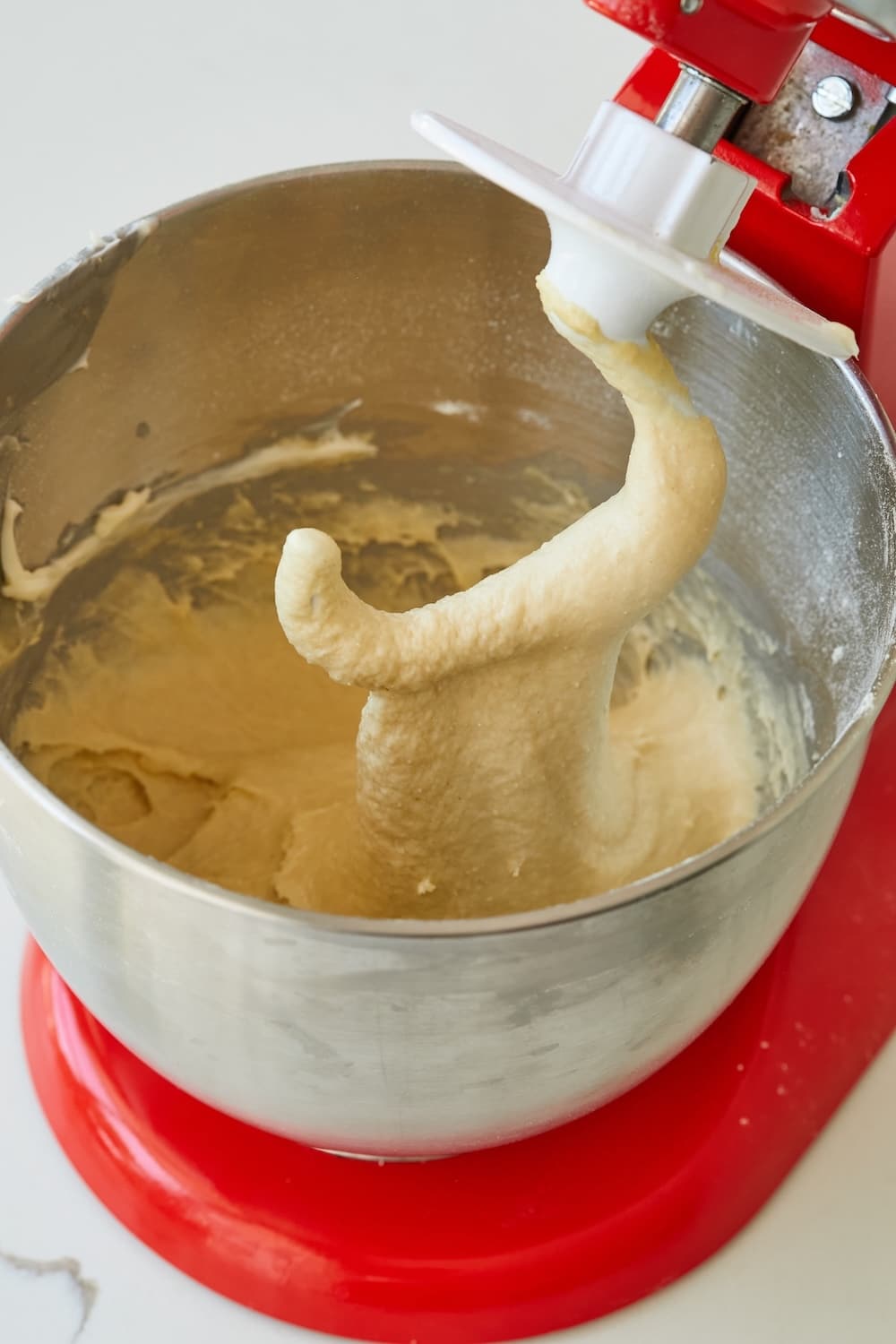 A soft Japanese Milk Bread dough formed in the bowl of a stand mixer with a dough hook. 