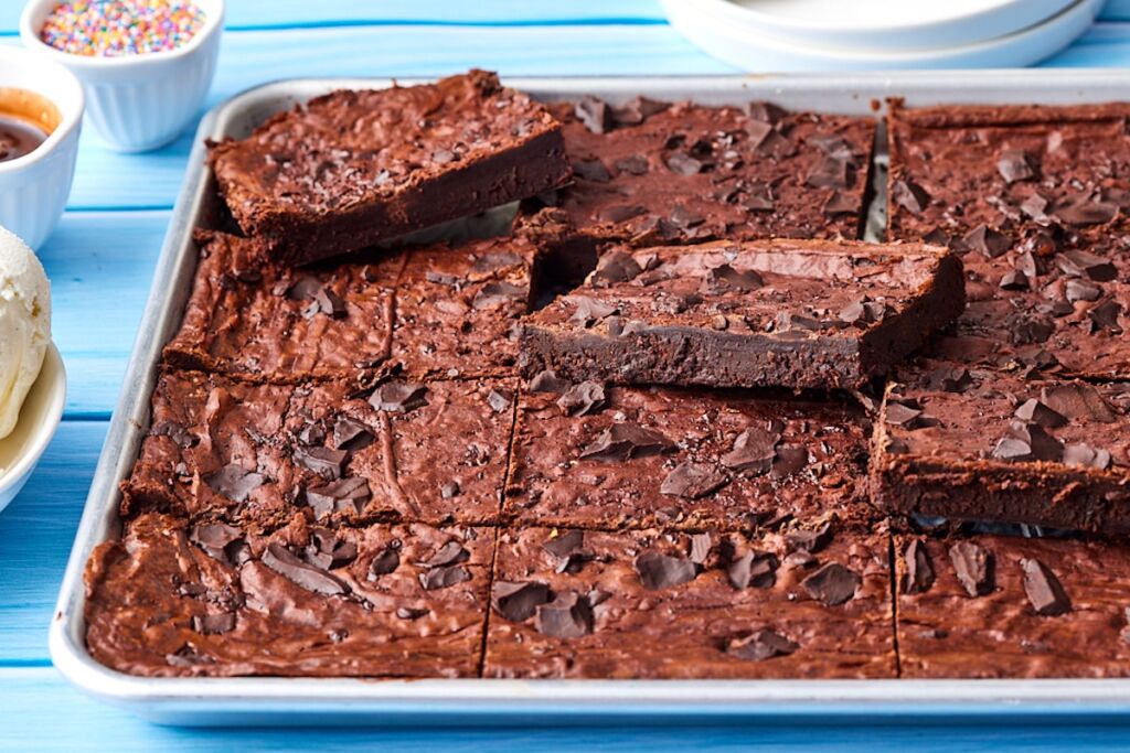 Sheet pan brownies with crackly top chewy edges and fudge center.