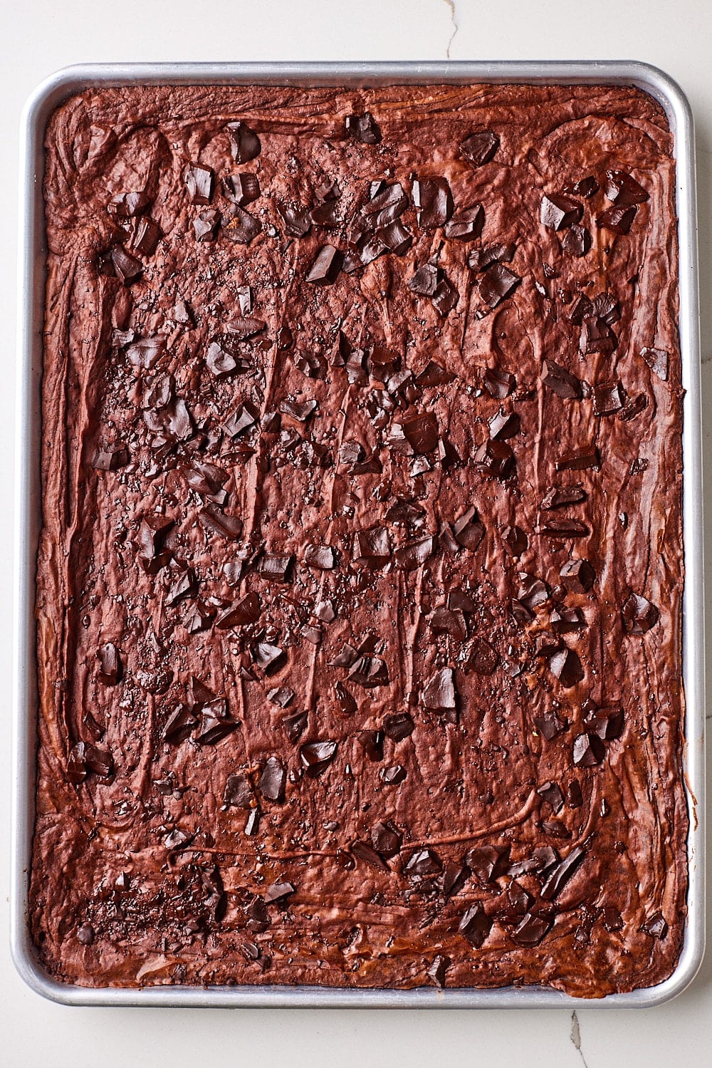 Top-down view of sheet pan brownies with crackle top and chunks of chocolate. 