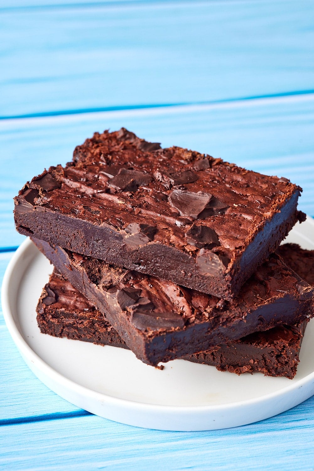 There big pieces of sheet pan brownies stacked on a dessert plate. 