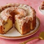 A glazed Strawberry Lemon Pound Cake with one slice cut and served on the side.