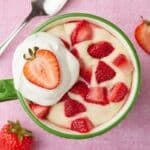 Top-down view of strawberry shortcake mug cake with fresh strawberries and whipped cream on top.