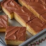 Squares of Tandy Cake in the baking pan, with layers of sponge cake, peanut butter, and chocolate.