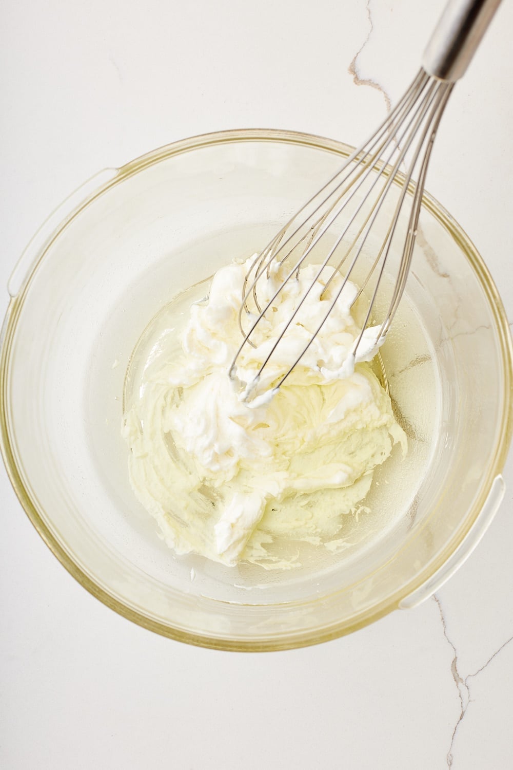 Oil is added to the yogurt with a whisk in the bowl. 