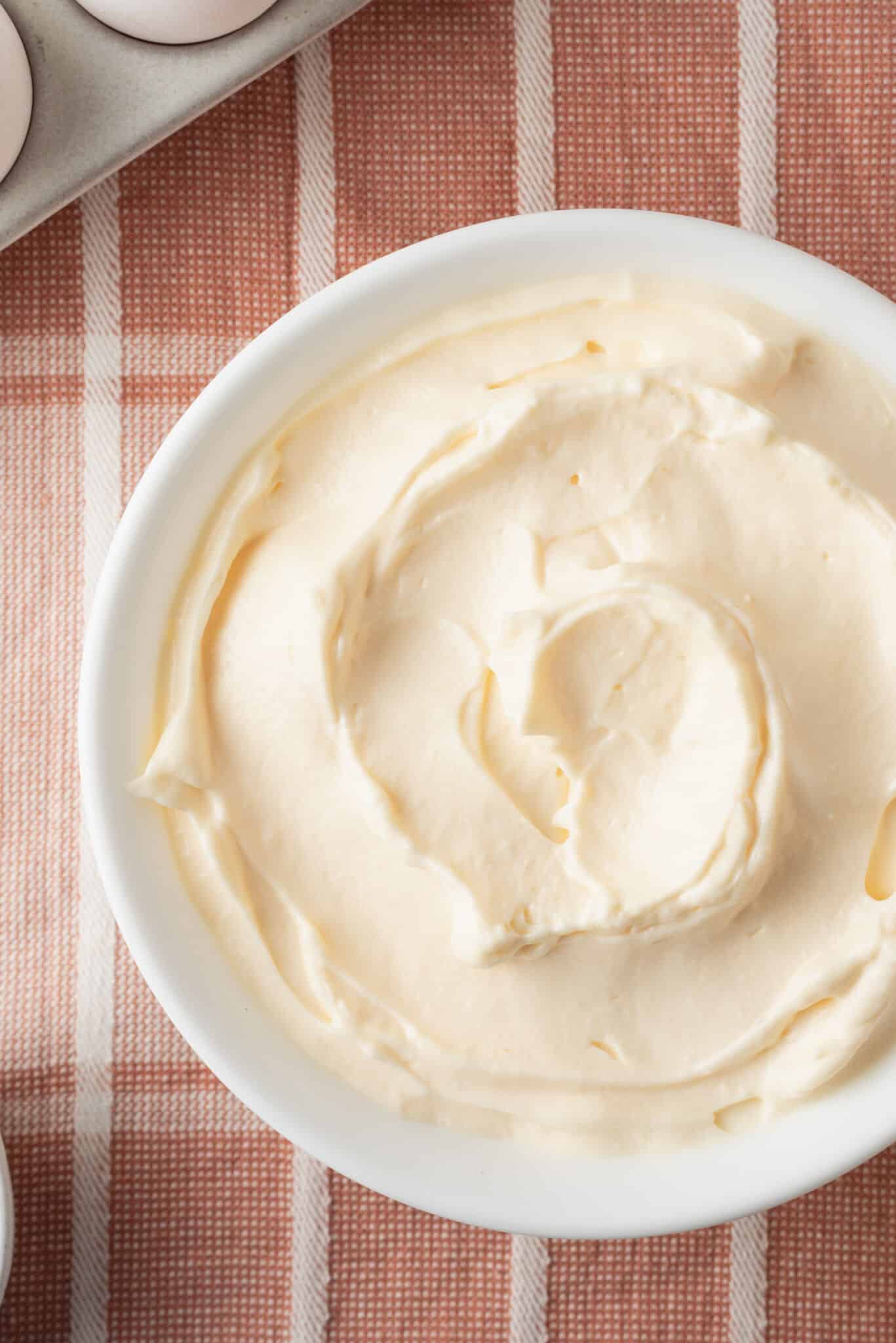 Top-dow view of a bowl of Homemade Mayonnaise with egg on the side. 