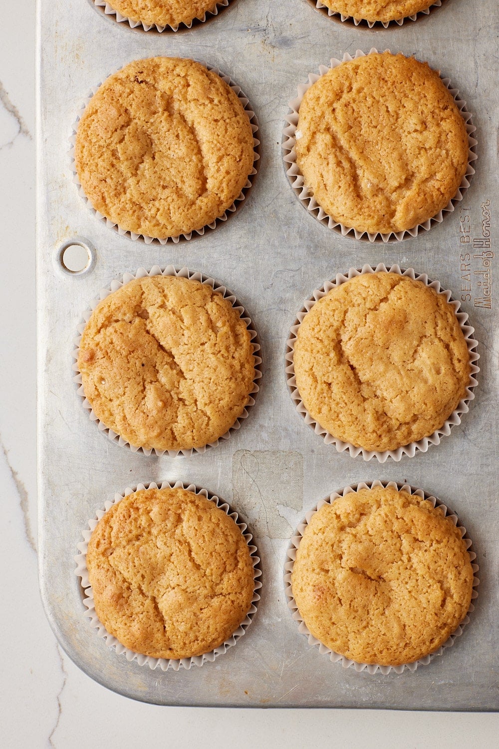 Apple Cider Muffins6 Top-down view of a tray of Apple Cider Muffins baked golden.