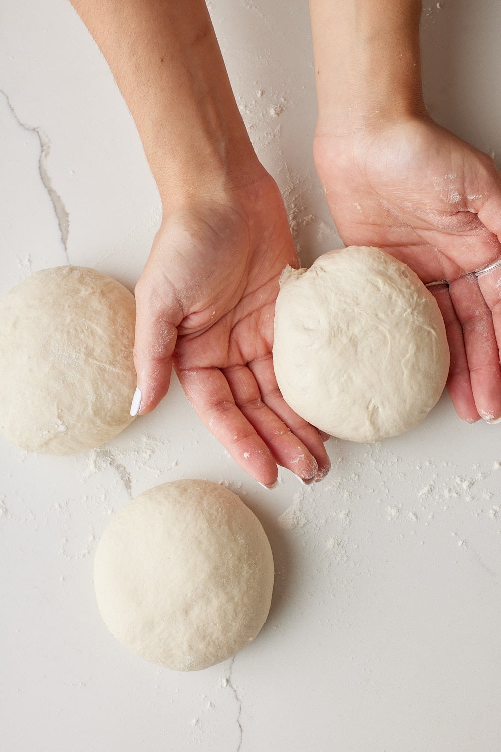 Batch Bread7 Hands shaping one of four dough balls for Irish batch bread on a lightly floured work surface.