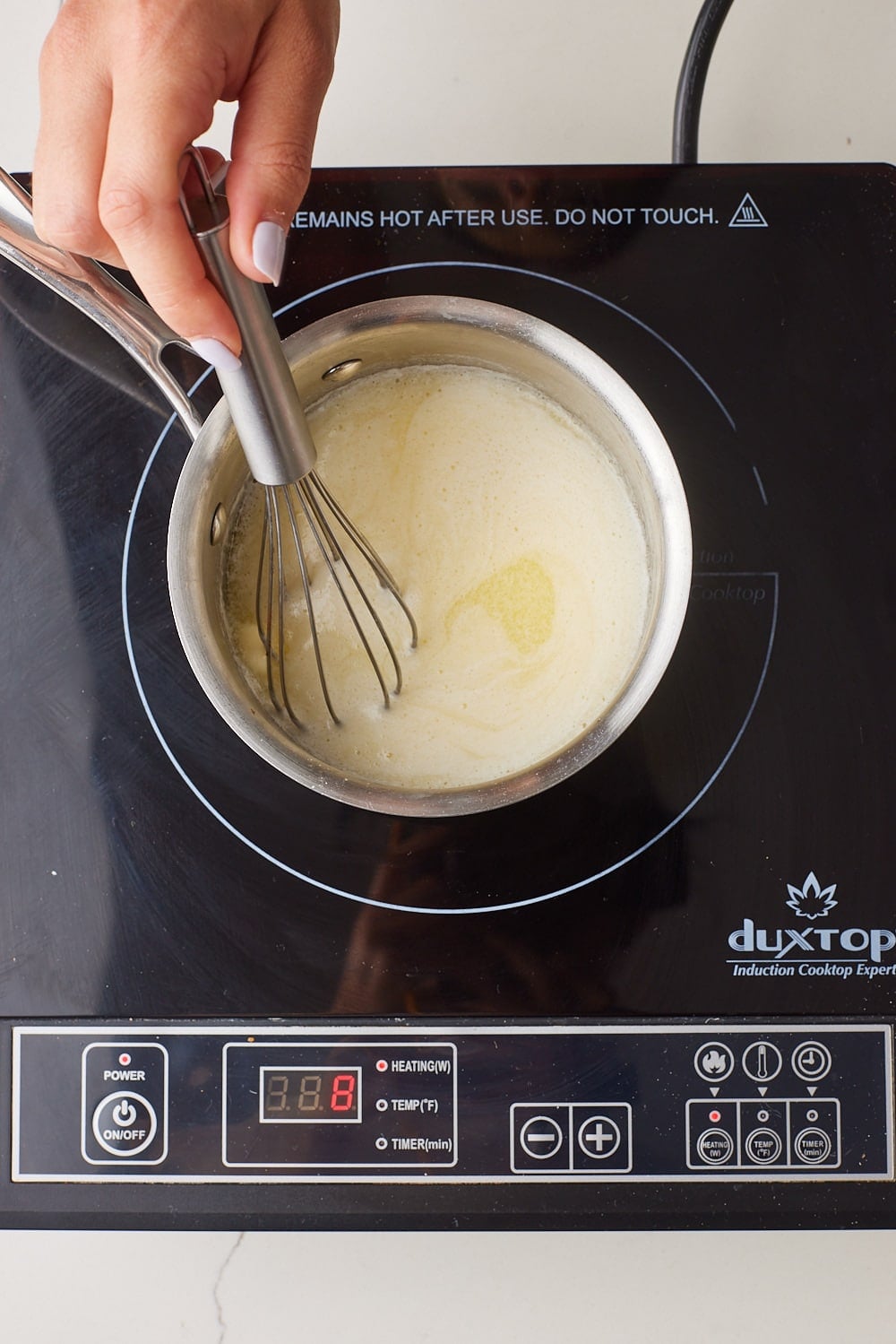 How to Make Brown Butter2 Hand whisking butter in a saucepan over an induction cooktop.