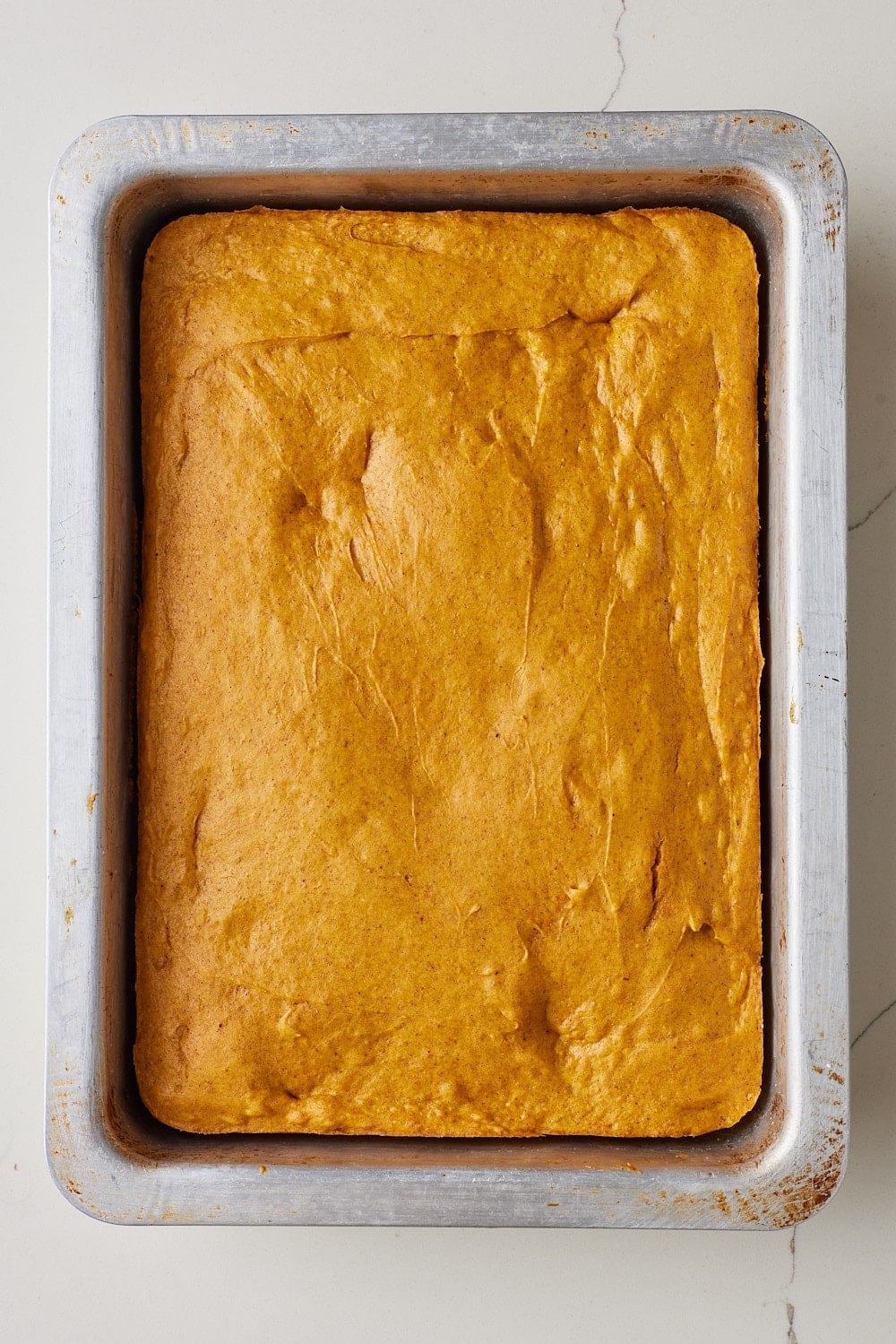 Pumpkin Spice Cake w Cake Mix4 Unfrosted pumpkin spice cake baked in a rectangular metal pan, with a golden-brown surface and soft, moist crumb.