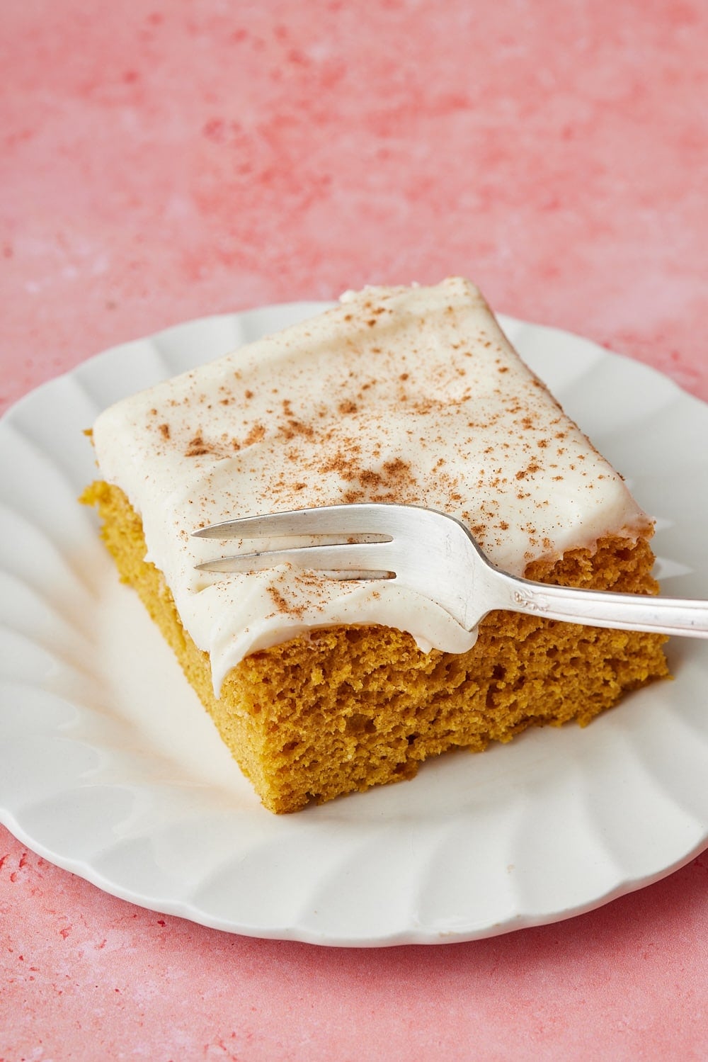 Pumpkin Spice Cake w Cake Mix6 Slice of pumpkin spice cake topped with creamy cream cheese frosting and cinnamon, served on a white plate with a fork.