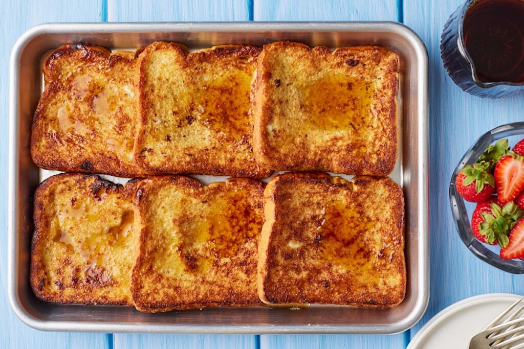 Sheet Pan French Toast with maple syrup and fresh strawberries.